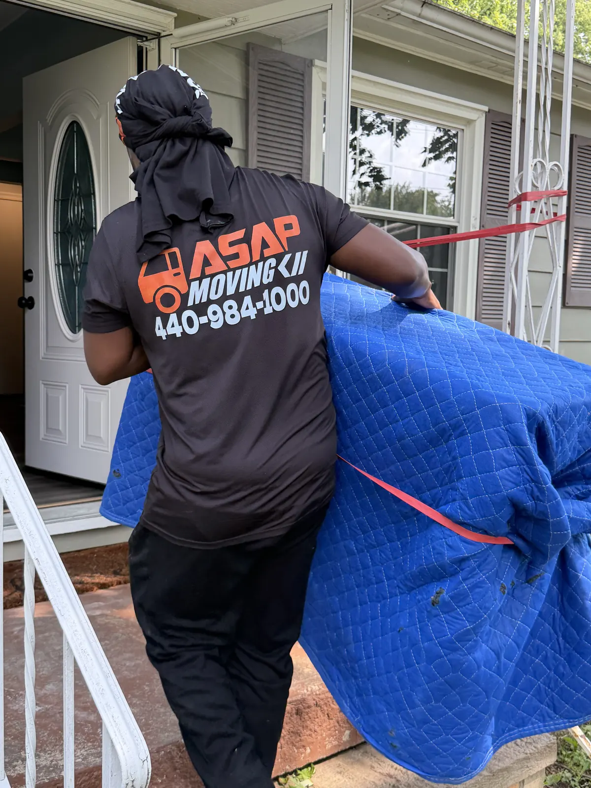 ASAP Moving crew member carrying blue-blanket-wrapped furniture through a doorway in Amherst, Ohio.